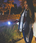 Person using High Lumen LED Flashlight With Adjustable Focus Beam From Spot To Flood 1002 Lumen in a nighttime outdoor setting