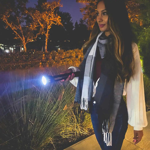 Person using High Lumen LED Flashlight With Adjustable Focus Beam From Spot To Flood 1002 Lumen in a nighttime outdoor setting