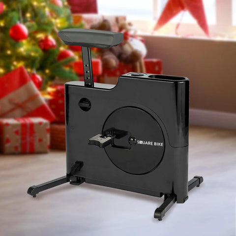 Black Felicity Compact Under Desk Exercise Bike With 8 Level Magnetic Resistance next to Christmas tree