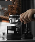 Game Changing 58mm Espresso Portafilter Station holding portafilter during tamping with ground coffee falling.