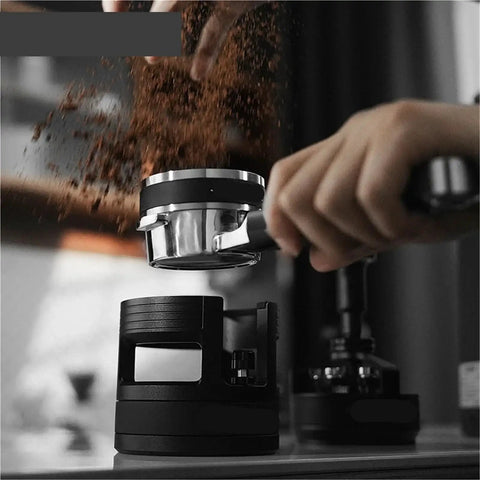 Game Changing 58mm Espresso Portafilter Station holding portafilter during tamping with ground coffee falling.