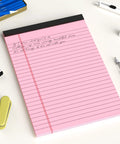 Five Pack 5x8 Legal Pads With Colored Covers Narrow Ruled Perforated Writing Pads For School And Office 30 Sheets Per Pad Great For Note Taking Studying And Quick Brain Dumps on a desk with pink paper and pens