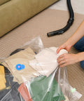 Person sealing clothes in Ultimate Vacuum Seal Kit For Compression Bags With Valve Plugs and Airtight Caps on carpet