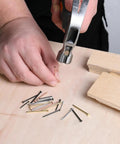 Pro Level Steel Nail Assortment Pack With 600 Pieces Across Four Different Sizes, hammering in a steel nail on wood.