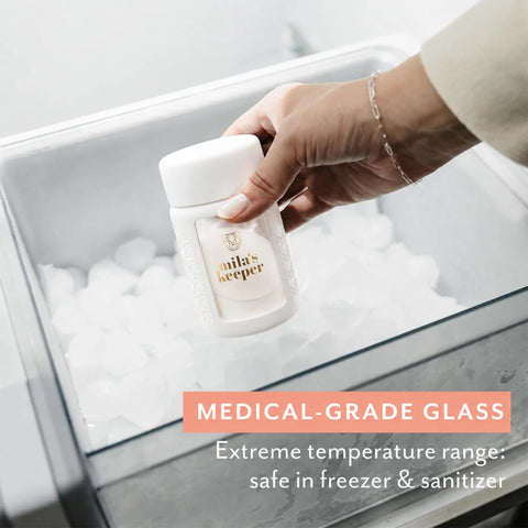 Hand holding a glass breast milk storage bottle in ice, showcasing the Ultra Wide Neck Glass Breast Milk Storage Bottles For Pumping And Feeding Bpa Free Silicone Caps Fit Most Pumps Aspen White Pair For Busy Mommas Keeping Fresh Stashes On Deck.