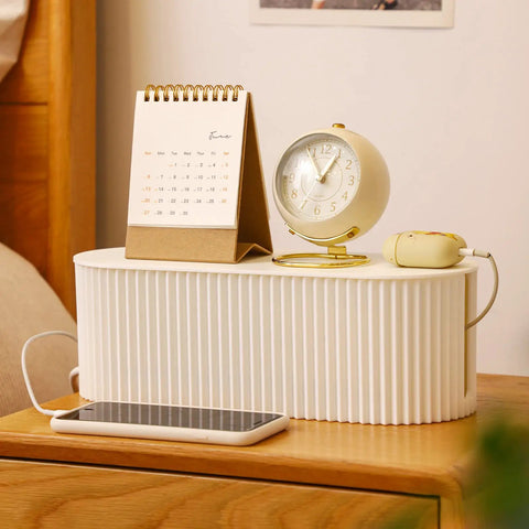 Cable Management Box With Ten Cable Ties For Organizing Power Strips And Surges Hiding TV And Computer Wires No More Wire Mess Keeps Cords Tidy And Heat Safe Perfect For Home Or Office Small White Cord Organizer on desk with calendar and clock.