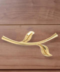 Gold ergonomic metal cabinet handle in leaf design on wooden drawer, ergonomic metal cabinet handles and drawer pulls for cabinets