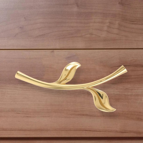 Gold ergonomic metal cabinet handle in leaf design on wooden drawer, ergonomic metal cabinet handles and drawer pulls for cabinets
