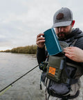 Angler adjusting Stormshadow Fly Fishing Chest Pack With Waterproof Pocket by river, highlighting tool attachment in use.
