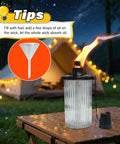 4 Pack Gray Glass Outdoor Garden Torches 59 Inch Tall With Upgraded 16 Oz Citronella Fuel 5 Prong Grounded Stake Metal Light Torches For Patio Pathway Party Decor And Create A Chill Backyard Vibe lit at night on a table with funnel and tent behind.