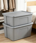Kickass 30 Gallon Heavy Duty Plastic Storage Bin With Secure Snap Lid For Garage Organization Seasonal Gear Sorting And Everyday Essentials In Matte Gray Finish stacked next to a bed.