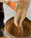 Man emptying Reusable Dust Bag For Festool Midi CT 15 E And CT 25 HEPA Dust Extractors into a large container.