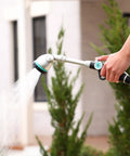 Person using 16 Inch Long Reach Watering Wand With 90 Degree Head Thumb Control And 6 Spray Patterns for watering plants outdoors.