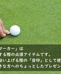 Person placing Swinging Bear Golf Ball Marker With Magnetic Hat Clip on golf course next to a golf ball.