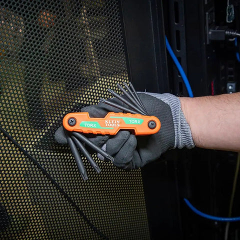 Gloved hand holding compact folding hex key set with 25 sizes in metric and SAE plus Torx keys, industrial-strength, orange handle.