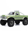 Badass 1/18 Scale RC Crawler With Slick Shifting Two Speed Transmission And Bulletproof Metal Gears Nasty Terrain Rock Climbing Rig Trail Smashin Setup Drop In Ready Convoy Medium Olive Green truck front view with large tires and chrome details.