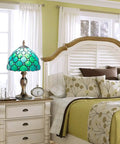 Stained Glass Table Lamp With Real Glass Shade In Green Pearl on a nightstand, antique Art Nouveau design in a bedroom setting.