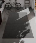 Shop Grade Heavy Duty Oil Spill Mat For Garage Floors 63 By 31 Inch Reusable Oil Absorbent Pad in a garage with bicycle and shadows
