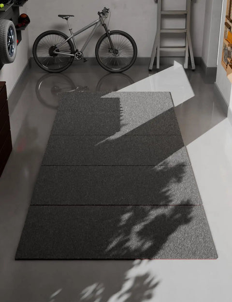 Shop Grade Heavy Duty Oil Spill Mat For Garage Floors 63 By 31 Inch Reusable Oil Absorbent Pad in a garage with bicycle and shadows