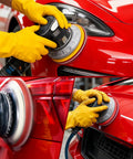 Person using 6-Inch Do-It-All Hook And Loop Sanding Sponges Discs 400-3000 Grit on a red car surface with a random orbital sander.