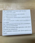 Box with multi-language warning label for adult supervision on wooden surface