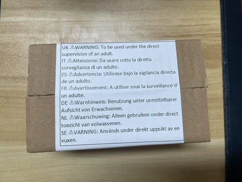 Box with multi-language warning label for adult supervision on wooden surface