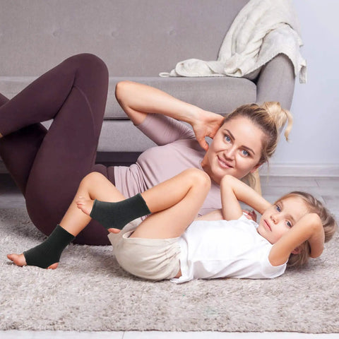 Mother and child exercising on carpet with Youth Ankle Compression Sleeve For Active Kids Knit Ankle Brace visible on child's ankle.