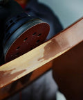 Close-up of 5 Inch 8 Hole Orbital Sanding Discs Set, 100 Pcs Hook And Loop Sandpaper for woodworking on furniture surface.