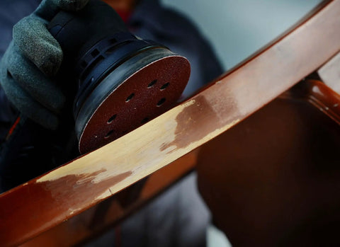 Close-up of 5 Inch 8 Hole Orbital Sanding Discs Set, 100 Pcs Hook And Loop Sandpaper for woodworking on furniture surface.