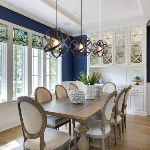 Dining room with three Farmhouse Black Globe Cage Pendant Light fixtures over wooden table, chairs nearby.