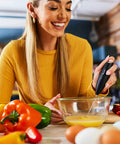 Woman using Powerful Handheld Milk Frother For Coffee Lovers, Quick Foam Maker Whisk beside fresh vegetables in kitchen.