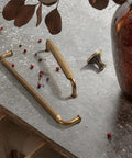 Antique Brass Zinc Alloy Cabinet Pulls 12 Pack Three And Three Quarters Inch Hole Centers Drawer Handles for Kitchen Cabinets and Dressers Vintage Vibe Durable Boss Grade Hardware on stone surface with vase