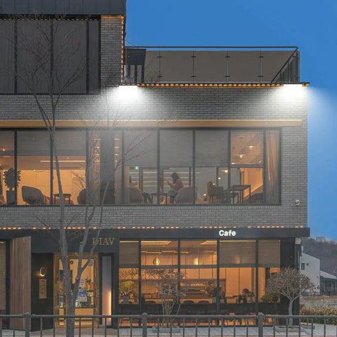 Beast Bright 150W LED Wall Pack Light With Photocell illuminating cafe facade, showcasing 19,500 Lumen Output, 5000K Daylight.