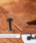 Close-up of a black self-tapping screw inserted into wood, part of 210 PC Carbon Steel Black Self Tapping Screws Kit M3.0 To M4.8 Pan Head With Washer Cross Drive Fasteners Assortment For General Hardware And DIY Projects.