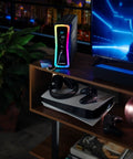 Gaming UPS Battery Backup And Surge Protector 1500VA 1000W next to gaming console and TV with RGB lighting on shelf.