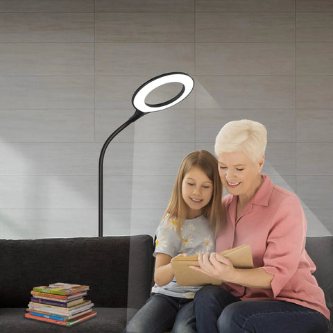 Gooseneck LED Floor Lamp For Office Reading And Bedrooms Non Glare Eye Safe Lighting 600 Lumens From 3 Watt LED Energy Saver Lit Brightness Ideal For Lash Extensions Makeup And Nail Spa Black, illuminating a reading area with two people sharing a book on a sofa.