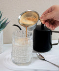 Pouring espresso from Go-To Stainless Steel Espresso Cup With Handle 3.4oz 100ml into glass, wide V-shaped mouth