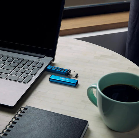 Rock Solid 16Gb Encrypted Usb Drive With Alphanumeric Keypad Lock next to laptop and coffee cup on table.