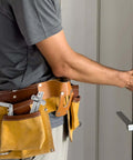Person installing Built Tough Stainless Steel Rotating Shaft Torque Pivot Hinges for Concealed Doors using yellow tool belt.