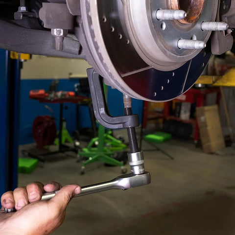 Premium Adjustable Ball Joint Separator And Puller Tool Knocks Stubborn Steering Joints Loose Up To Two Three Eight Inches For Cars Trucks Suv With Zero Headache No Sweat Garage Essential in use on vehicle suspension.