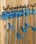 Heavy Duty Wall Mounted Pipe Clamp Rack That Keeps Clamps In Line Built From Galvanized Steel Holds Nine Pipe And Bar Clamps Up To 0.30 Inches Wide Organizes Your Workshop And Frees Up Space Like A Boss, holding clamps on a wooden wall.