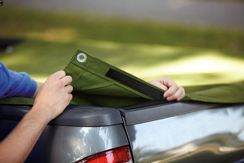 Person using Beefy Black Scotch Extreme Fasteners 10 Ft By 1 In Heavy Duty Velcro Bond on green tarp over truck bed