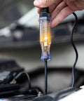 6V-12V-24V DC Car Electrical Test Pen With Alligator Clip And Long Steel Probe, Continuity And Voltage Fuse Tester For Sedan, SUV, RV And Truck, Handy Automotive Test Light For Quick Circuit Checks. Hand holding lit probe on car battery terminal.