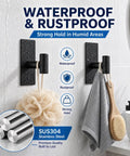 Five Pack Heavy Duty Adhesive Wall Hooks With Removable Strips For No Damage Hanging In Bathrooms Showers Outdoor Use Stainless Steel 304 In Black Durable Hooks For Towels Robes Hats And More Each Pair Holds Up To 8 Lbs With Two Strips displayed holding a loofah and towel in a wet bathroom setting.