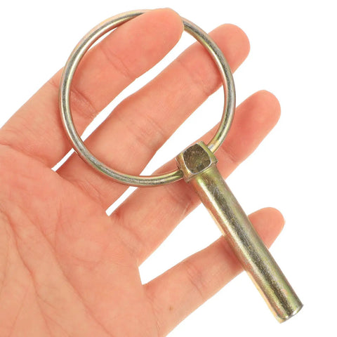 Hand holding a single galvanized pin from the Heavy Duty Lynch Pin Kit With Rings, 16 Galvanized Retaining Pins For Farm Tractors, Trailers, And Mowers.