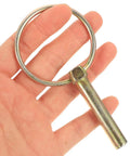 Hand holding a galvanized Lynch Pin Kit with Ring from a 16 piece heavy duty safety pins set for tractors and trailers.