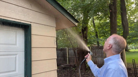 Man using Heavy Duty Garden Hose 5 Ft 5/8 Inch Female To Female Connector Black Water Hose for watering near garage