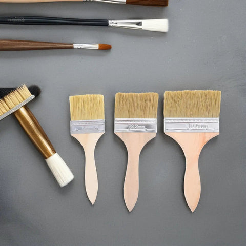 Wood Handle Paint Brush Set, 3 Pack Flat Stain Brushes For Furniture And Wood, sizes 2.5, 3, 4 inch, on a grey surface with other brushes