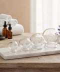 Deluxe 4 Piece Glass Cupping Set With Fire Cupping Jars Vacuum Therapy 4 Sizes And Handy Finger Grips on countertop