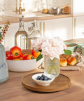 9 Inch Acacia Wood Lazy Susan Turntable Organizer For Cabinets And Pantry Shelves holding a bowl of blueberries on a kitchen counter